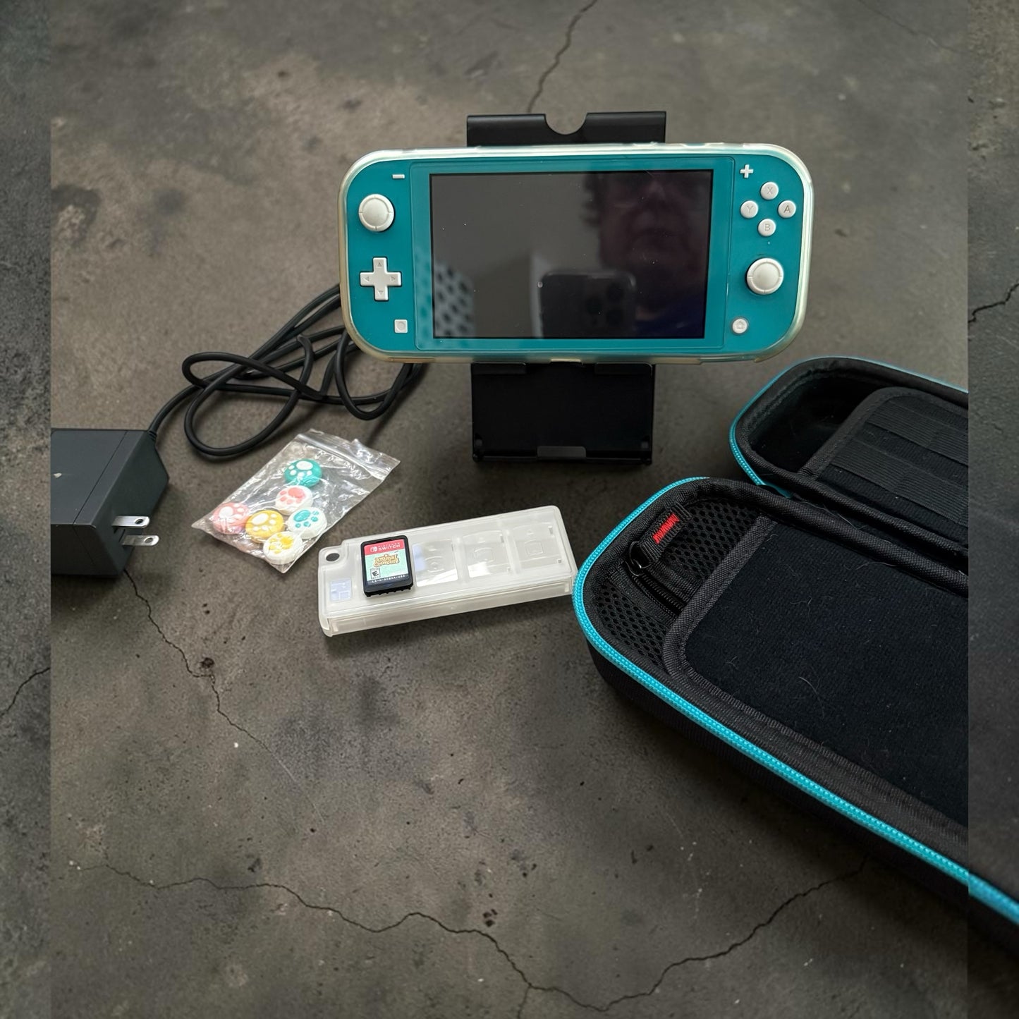 Fire Girl Design turquoise Nintendo Switch Lite bundle with carrying case, power adapter, game holder, and thumb grips.